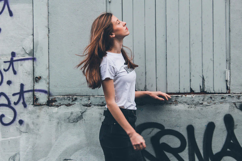 Stylish woman in a white t-shirt leaning against a wall