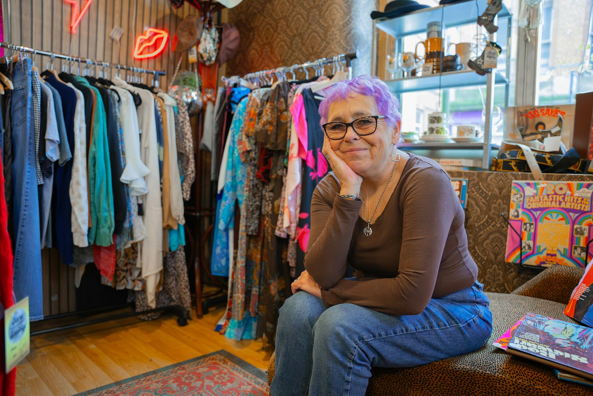 A customer sitting on a bench in a boutique clothing store, the kind of considered retail experience a calm Shopify checkout supports