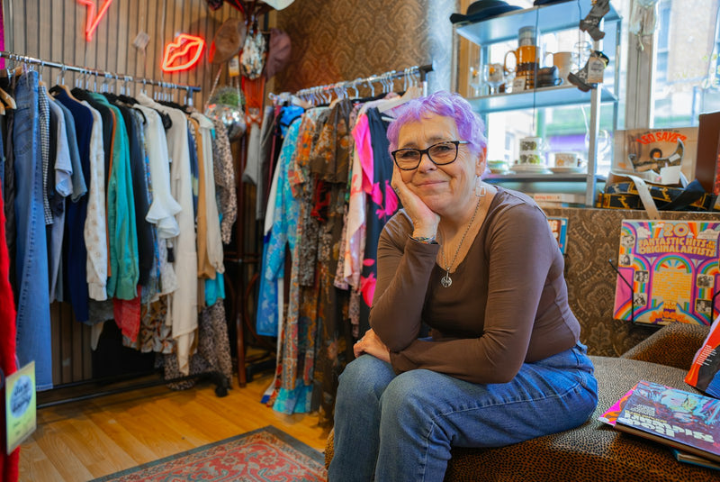 A customer sitting on a bench in a boutique clothing store, the kind of considered retail experience a calm Shopify checkout supports