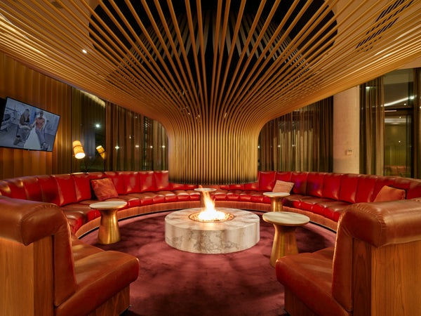 Circular lounge with a central fireplace and red sofas, sophisticated members club interior