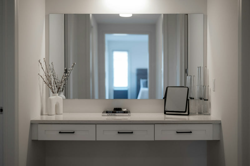 A modern dressing-room vanity with a large mirror and considered decor, evoking the kind of polished routine a luxury skincare customer enjoys